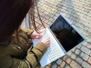 Frau mit Laptop auf dem Schoß auf der Straße