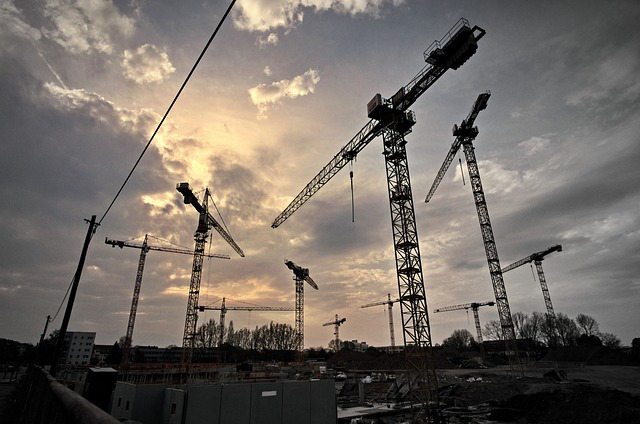 Für neues Wohnen in München: Baukräne im Spiel aus Sonne und Wolken