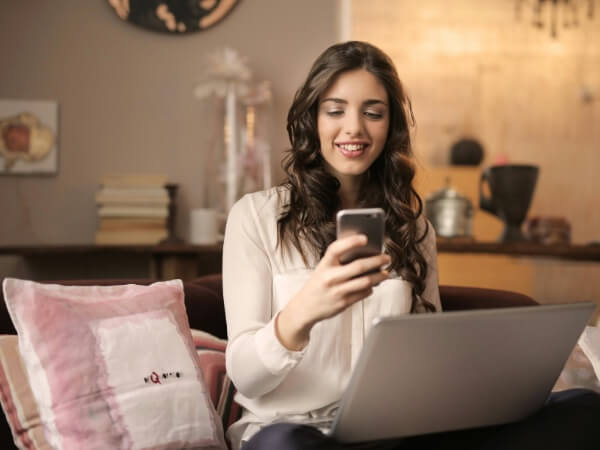 Frau sitzt mit Smartphone auf dem Sofa