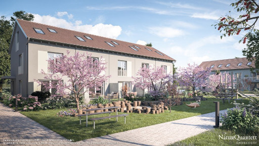 Eine Reihenhaussiedlung mit blühenden Kirschbäumen und Grünflächen in der Mitte. 