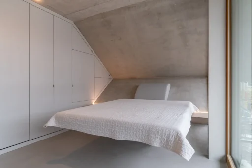 Ein Blick ins Schlafzimmer der Wabe: Das Bett ist an der schiefen Ebene am Ende des Raums befestigt, die seitliche sechseckige Wand ist als Einbauschrank gestaltet.