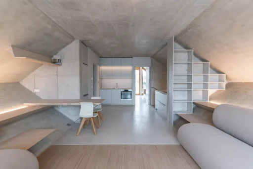 Wohn-Essbereich im Inneren des Wabenhauses. Die schiefen Ebenen sind als Sitzbänke gestaltet, die Wände sind "roh" im Loft-Stil.