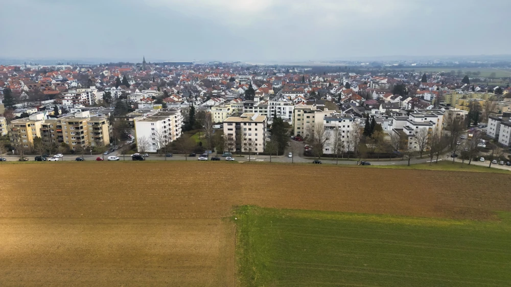 Luftaufnahme einer Ackerfläche neben einer vielbefahrenen Straße am Westrand von Leinfelden-Echterdingen. Im Norden dichte Wohnbebauung. 