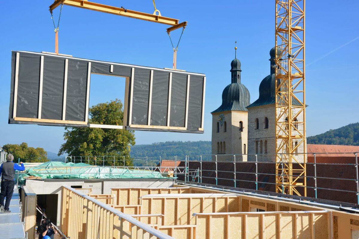 Kran setzt Wandelement aus Holz in den entstehenden Neubau der Benediktinerabtei Plankstetten ein.