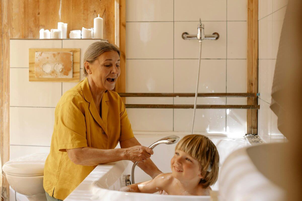 Erwachsener wäscht ein Kind in einer Badewanne. 