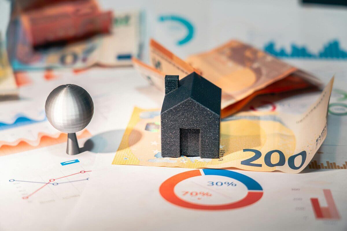 Ein 3D-gedrucktes, schwarzes Miniatur-Haus steht auf einem 200-Euro-Schein. 