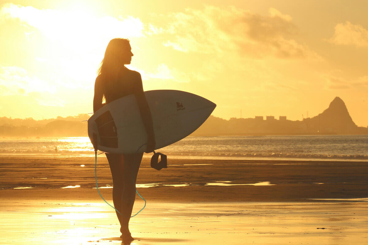Frau mit Surfboard am Strand
