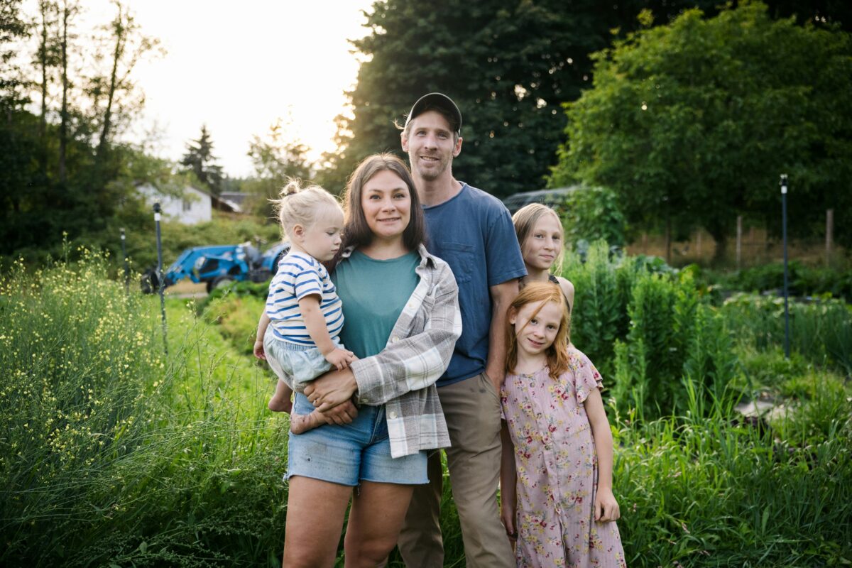 Eine Familie mit drei Kindern steht in einer Grünanlage.